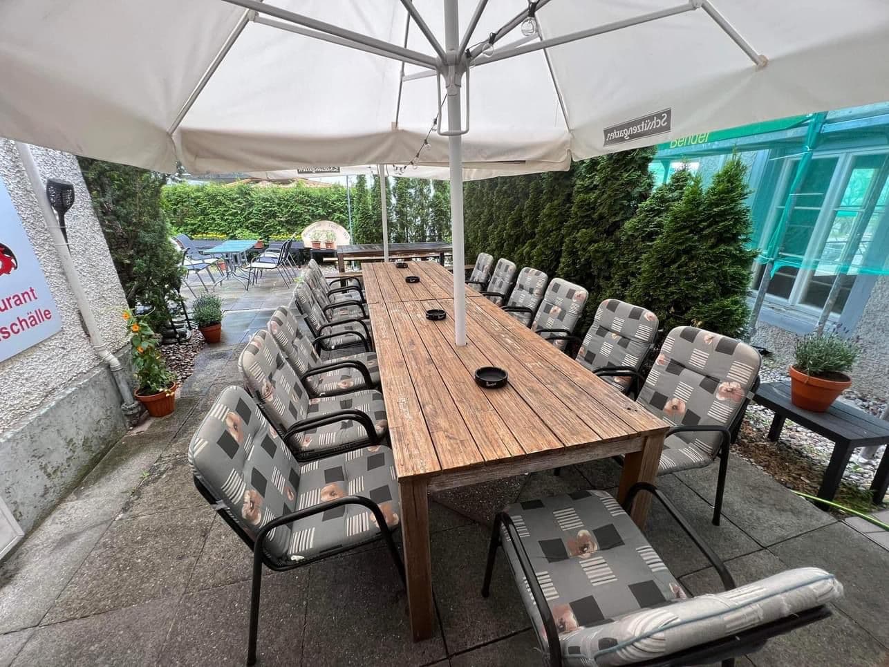Grosser Tisch unter Sonnenschirmen im Garten