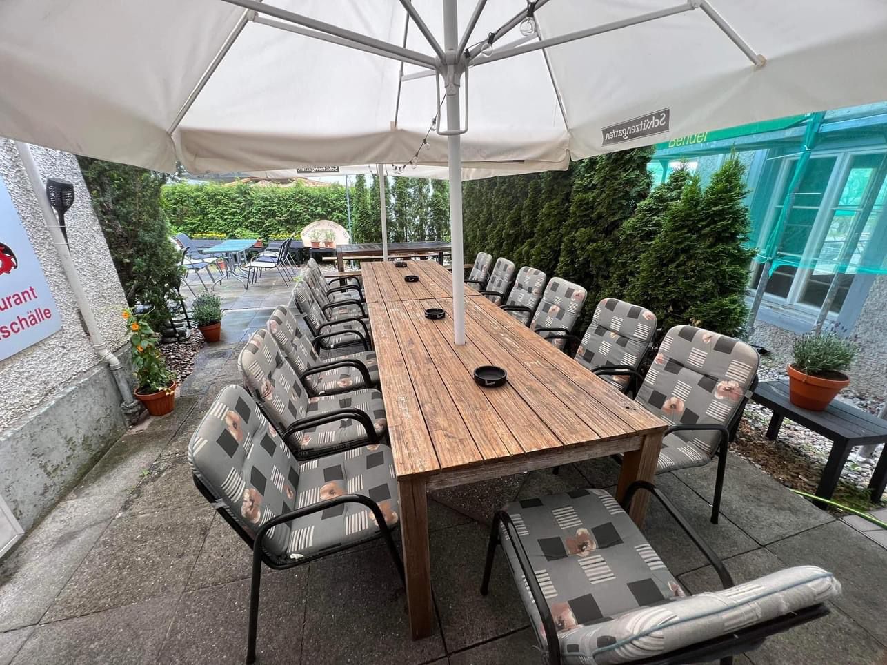 Grosser Tisch unter Sonnenschirmen im Garten